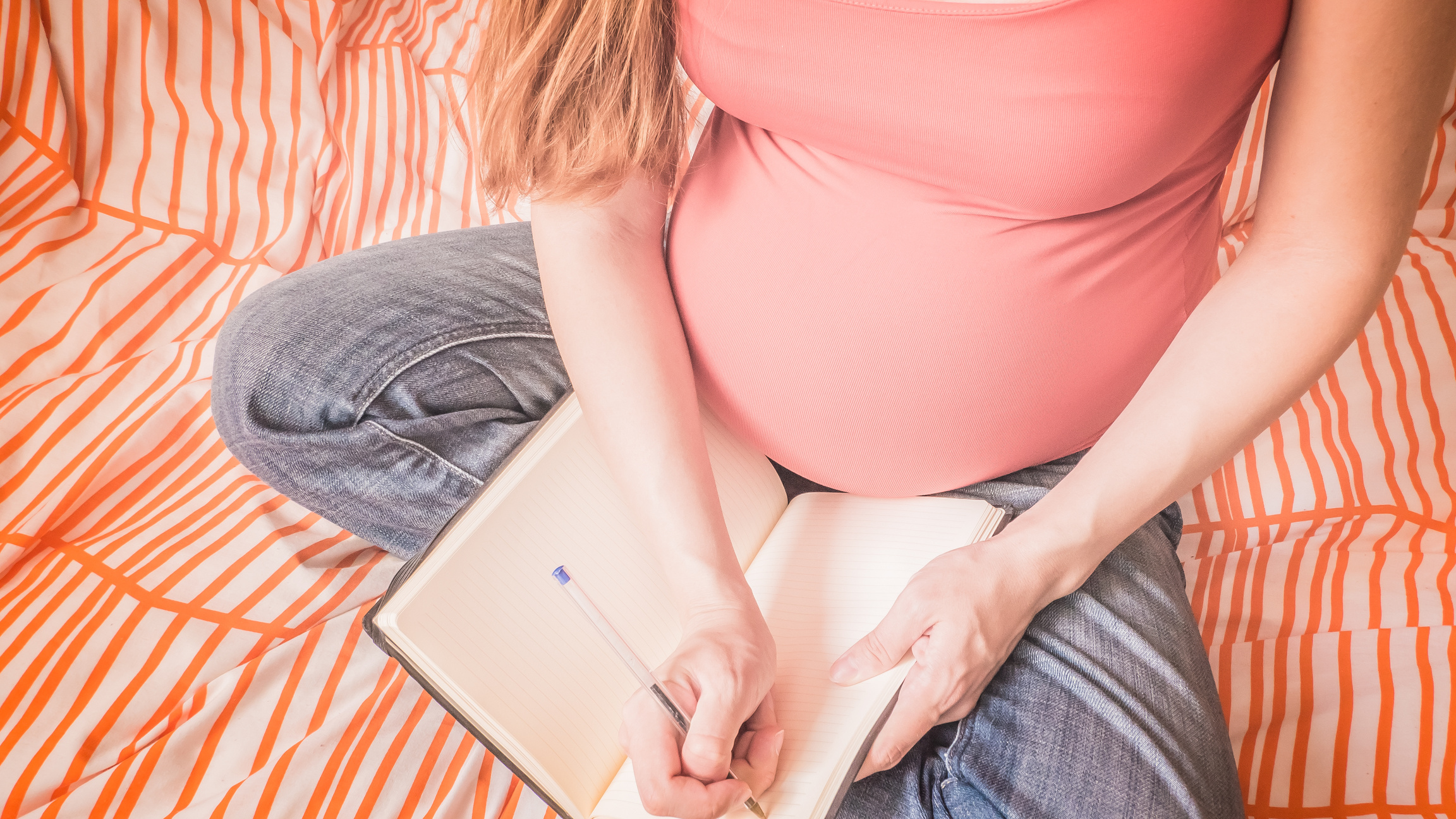 Pregnant woman is handwriting a birth plan at home
